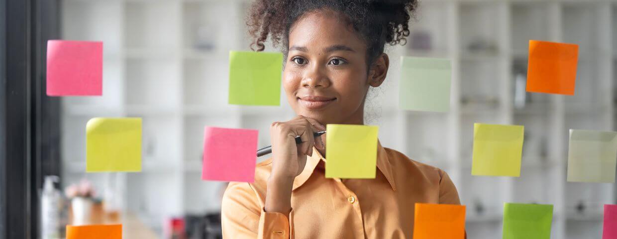woman brainstorming using sticky notes on glass wall 