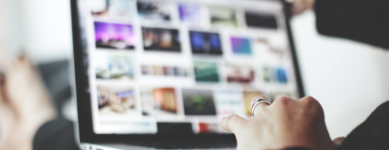 woman's hand on laptop with images blurred in background